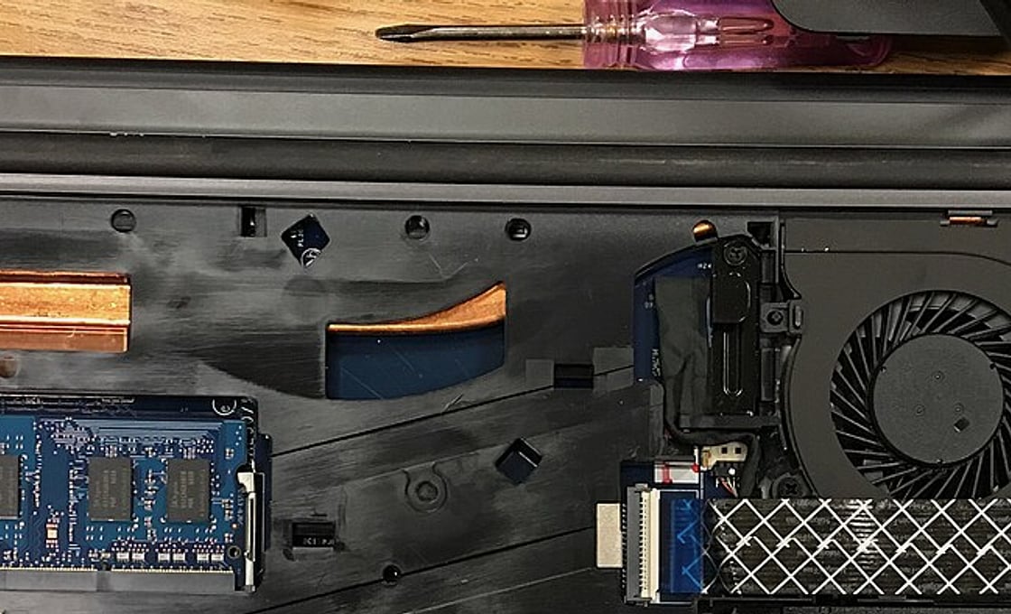 Kompartemen internal laptop yang dibuka di meja kerja servis HARDCARE, memperlihatkan modul RAM SO-DIMM, pipa pendingin tembaga, kipas, dan obeng presisi.
